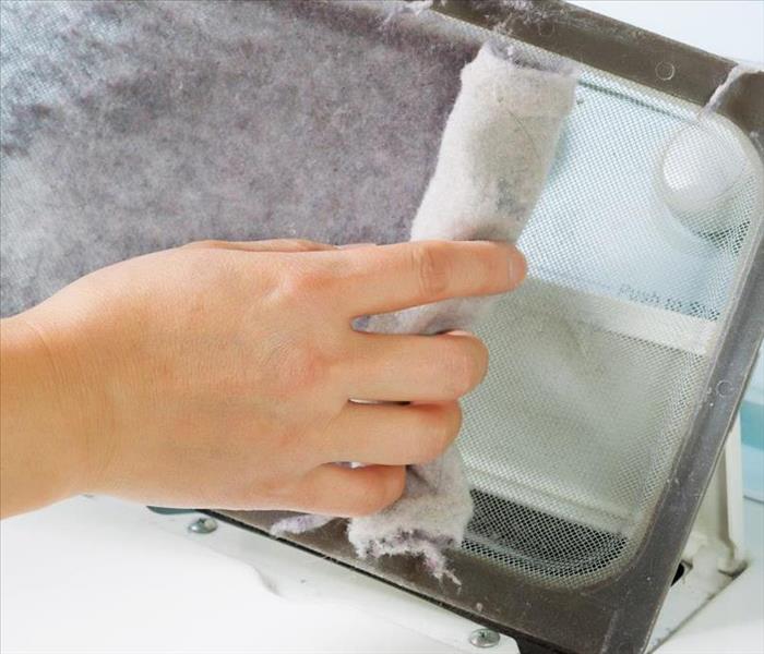 photo of a hand removing lint from a clothes dryer lint trap